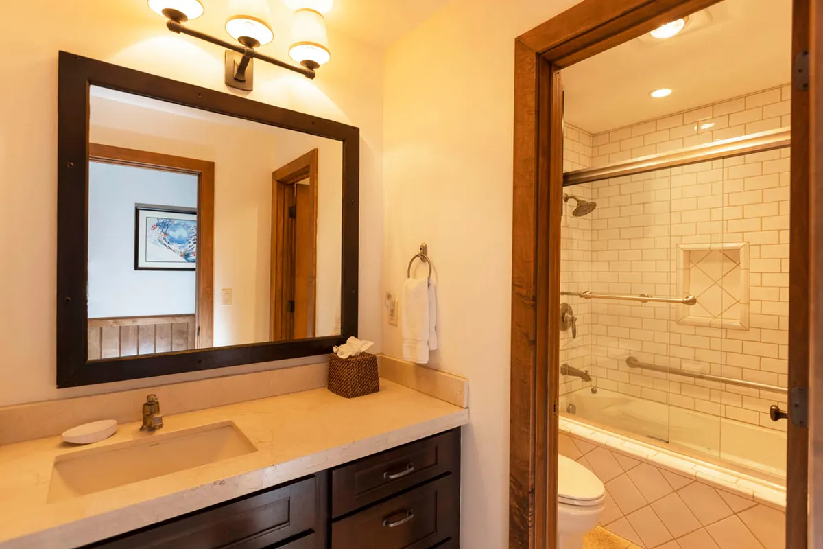 A modern bathroom with a spacious vanity, large mirror, and a glass shower area. The serene design and functional layout promote a refreshing and efficient morning routine.